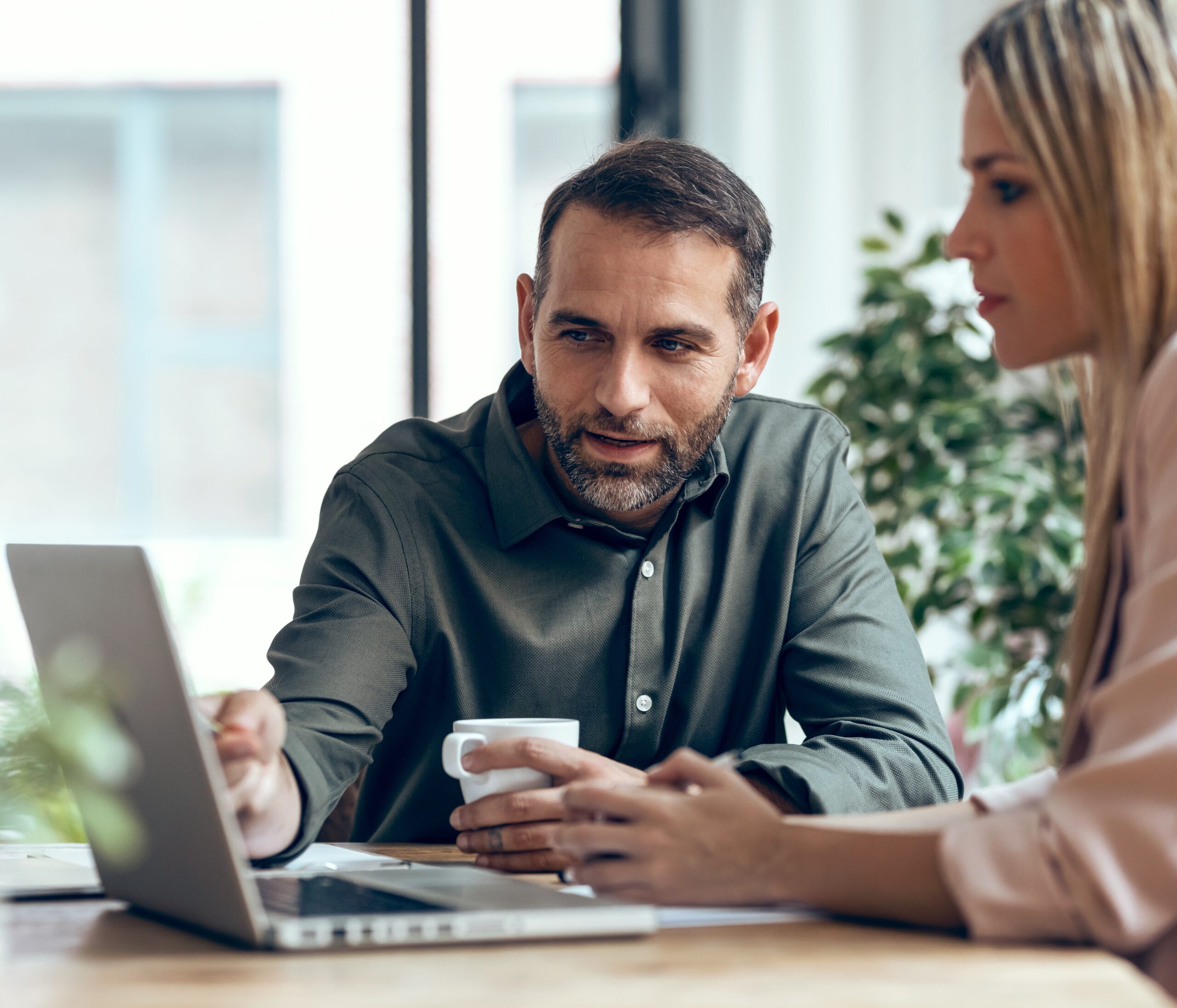 Coworkers talking while working on a laptop, 2