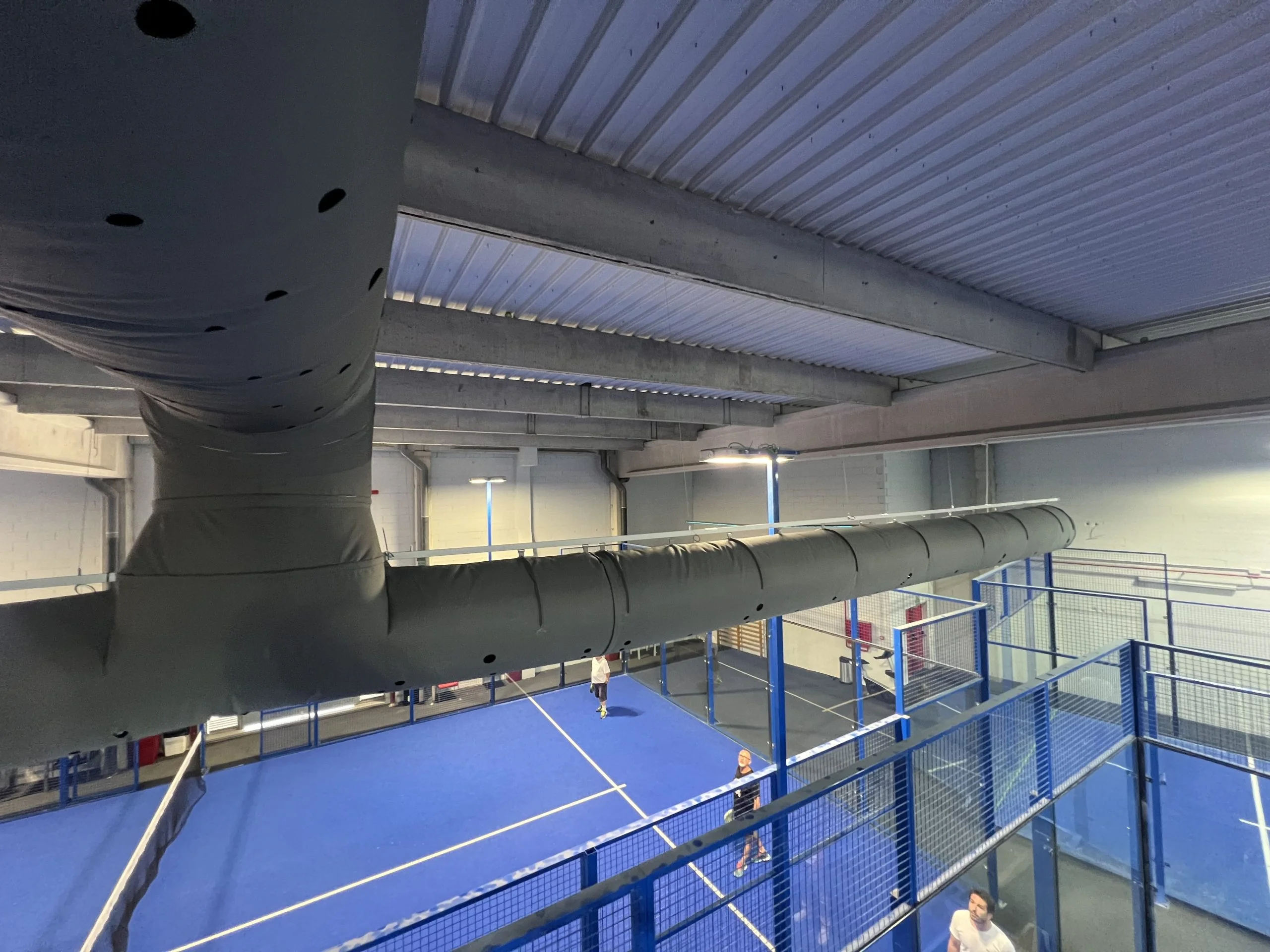 Black air ducts installed inside an indoor tennis court