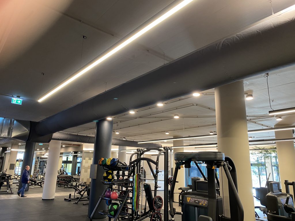 Fitnessstudio LOVT in Wien mit schwarzem textilkanal Lüftungssystem unter der Decke über dem Trainingsbereich, Österreich, 2