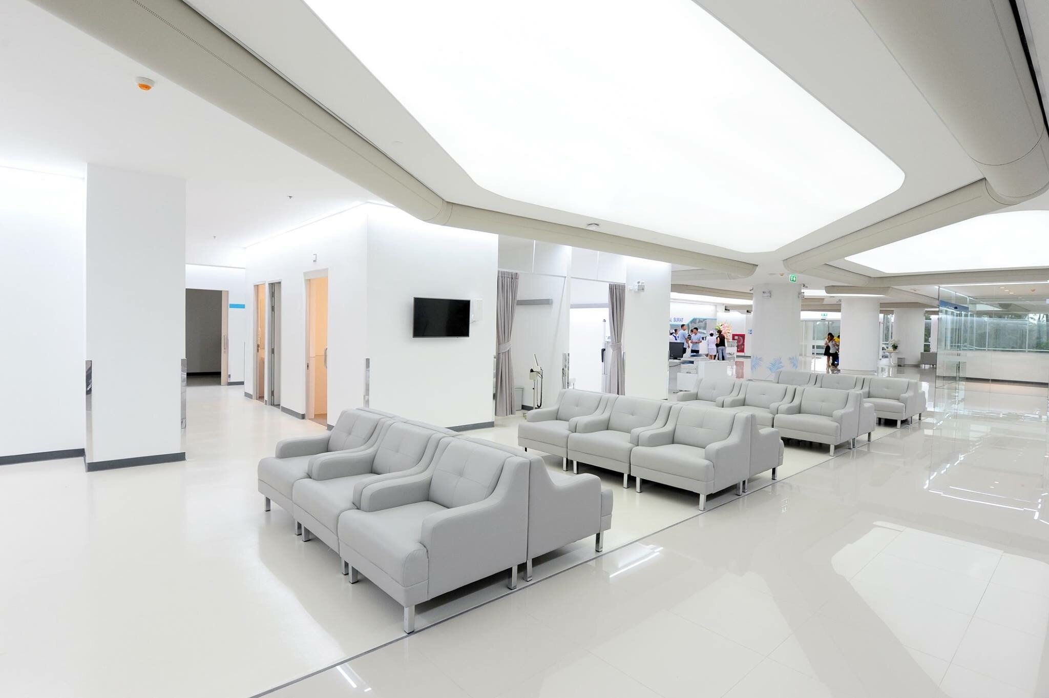 Heller Wartebereich im Krankenhaus mit Sitzgruppen und umlaufendem Textil-Luftkanal entlang der Decke.