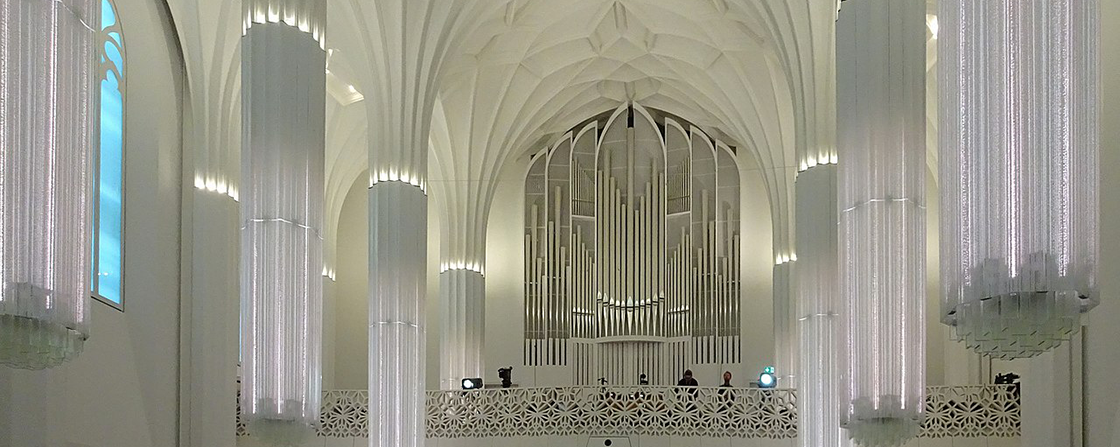 Kirchenraum mit hohen Gewölben und großen vertikalen textile luftauslässe, die als architektonische Elemente integriert sind.
