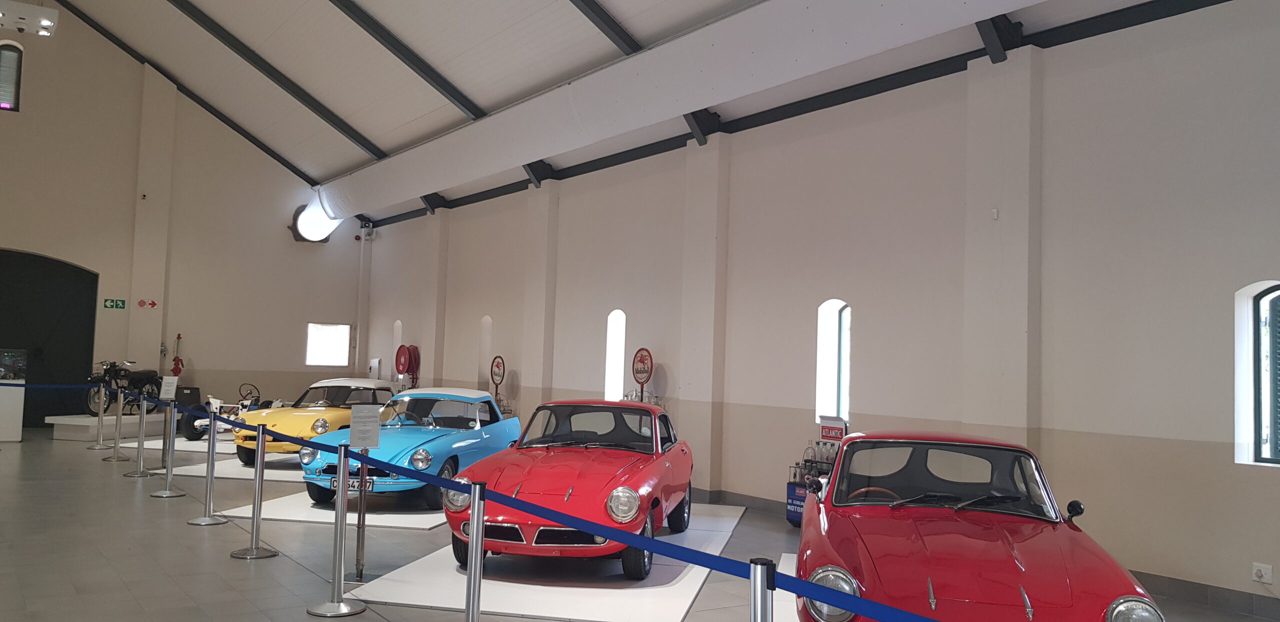 Oldtimer-Ausstellungshalle mit klassischen Fahrzeugen und weißem Textil-Luftkanal entlang der Decke.