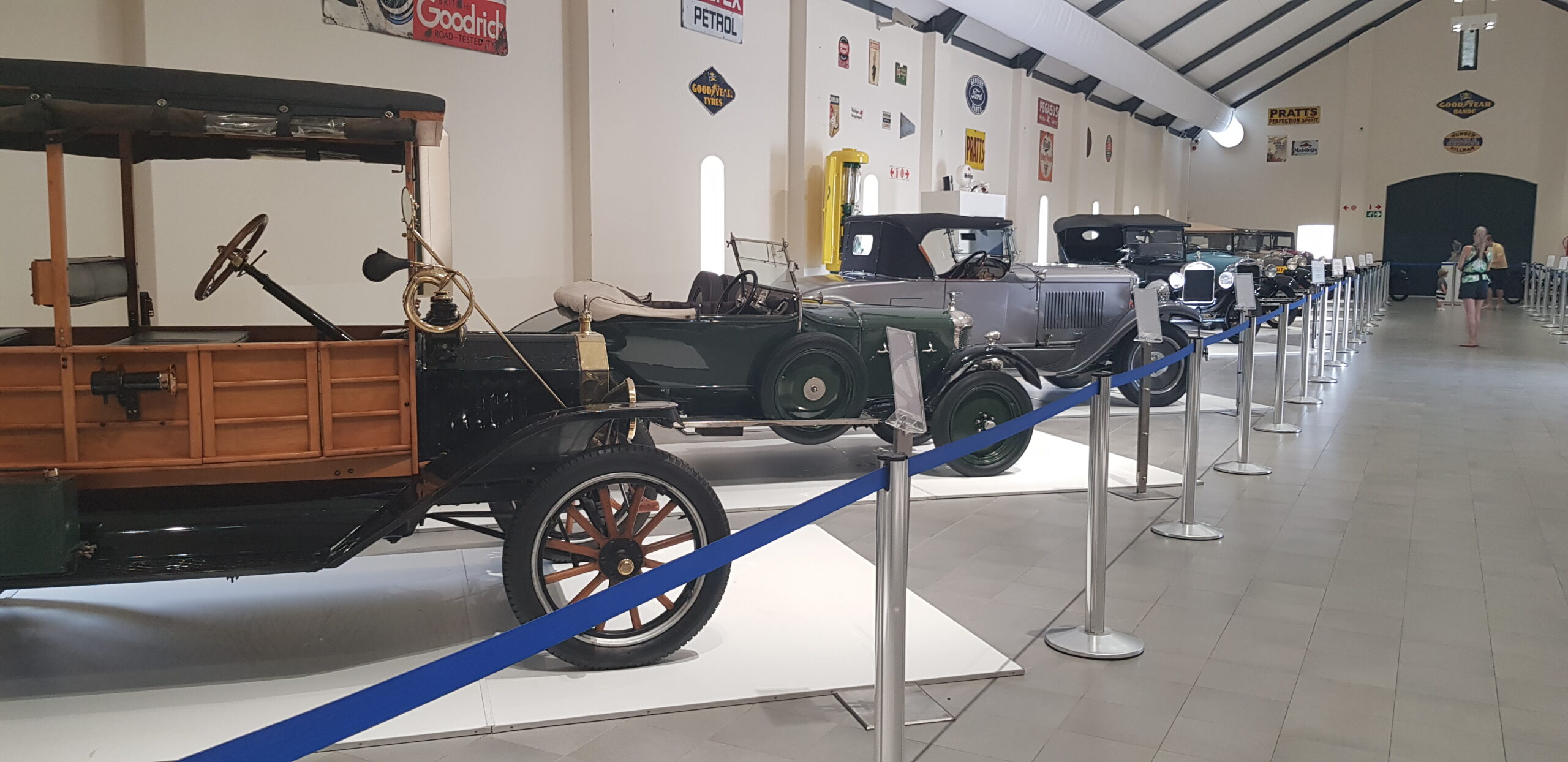 Oldtimer-Ausstellung mit historischen Fahrzeugen in einer modernen Halle, Besucherbereich mit Absperrungen und hohen Decken.