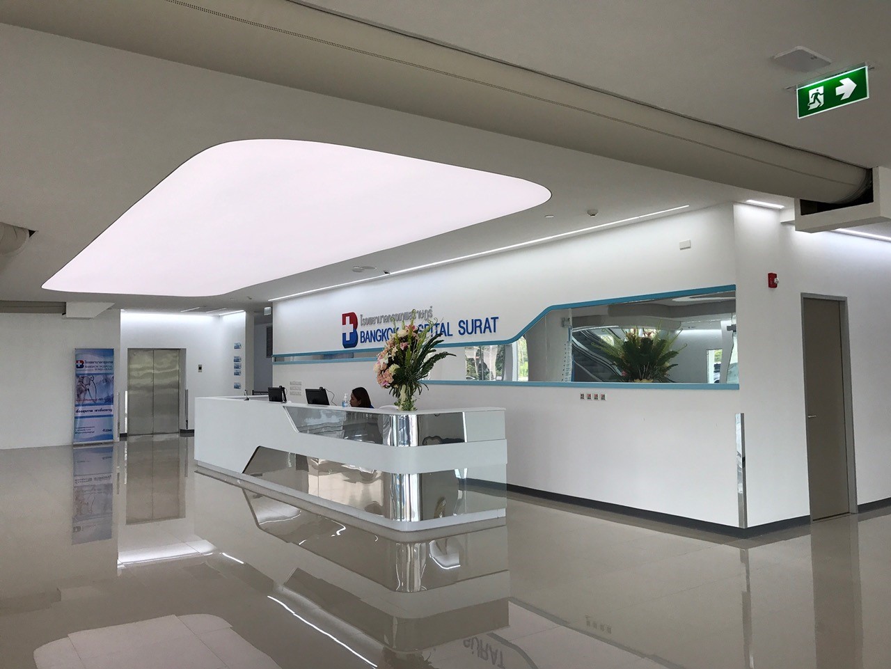 Empfangsbereich eines Krankenhauses mit reflektierendem Boden und geschwungenem Textilkanal über der zentralen Zone.