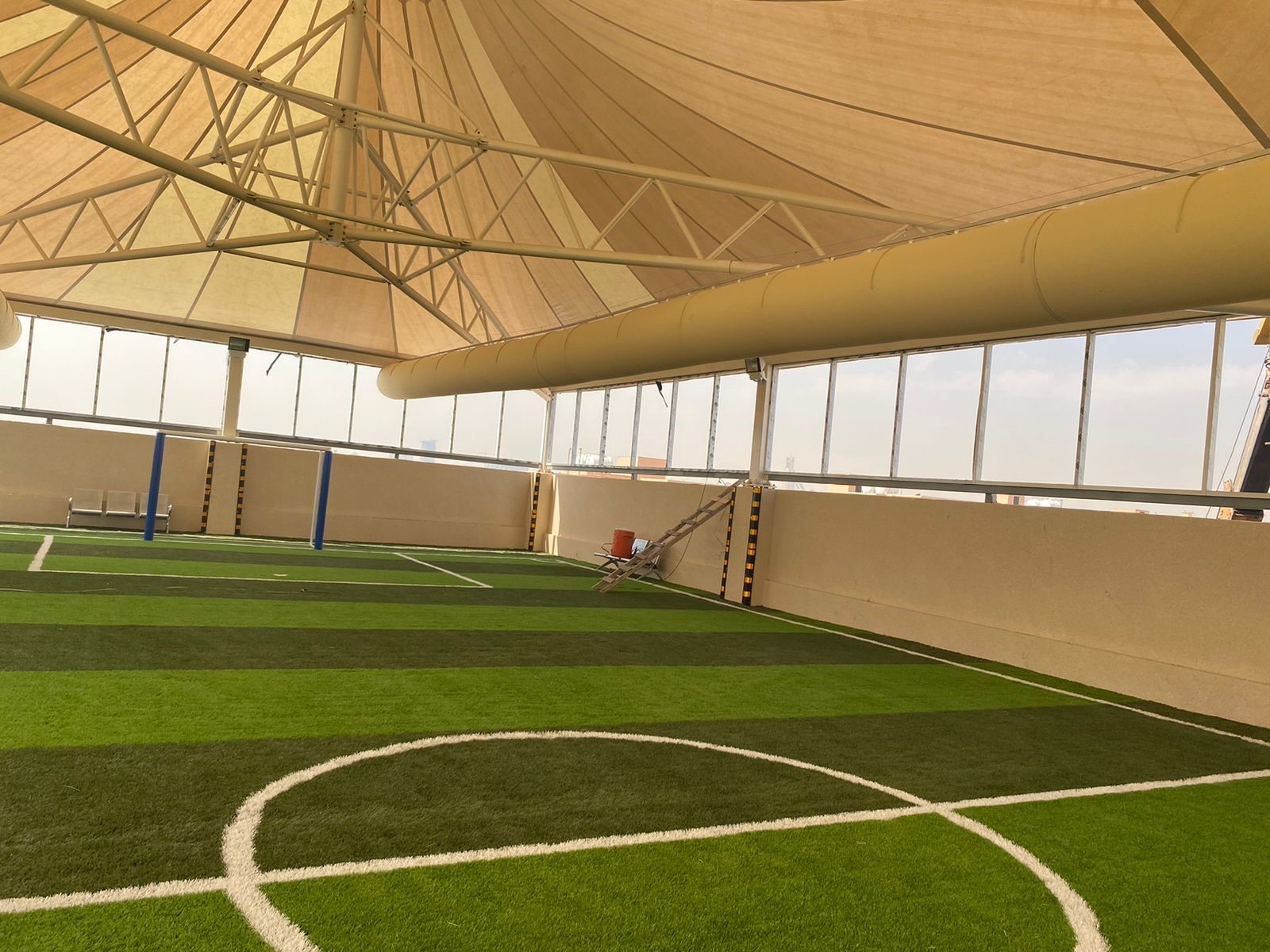 Sporthalle mit gespanntem Membrandach und umlaufendem Textilkanal zur gleichmäßigen Luftverteilung über dem Spielfeld.