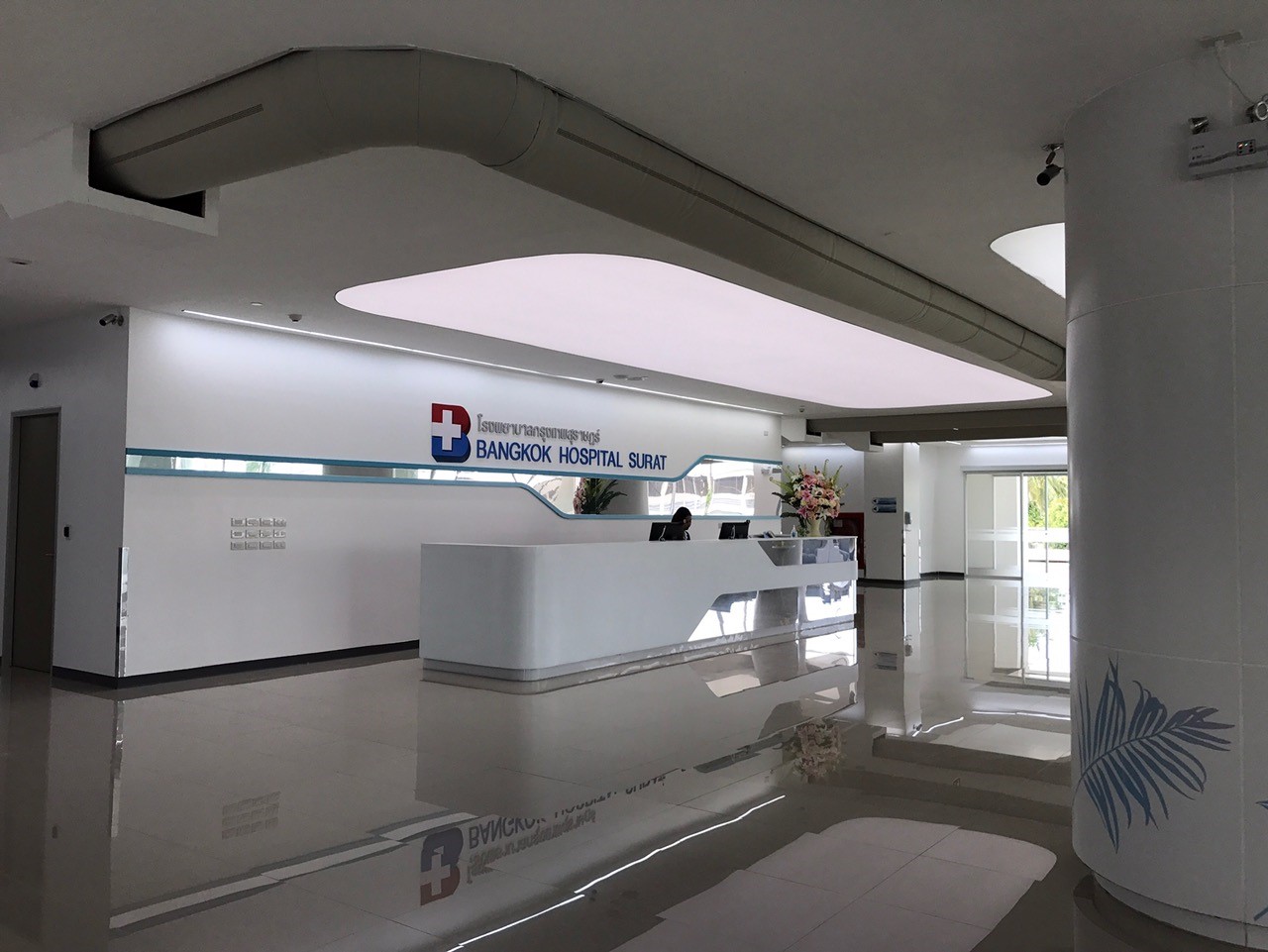 Moderne Krankenhauslobby mit Empfangstheke und gebogenem Textilkanal, der sich entlang der Deckenarchitektur zieht.