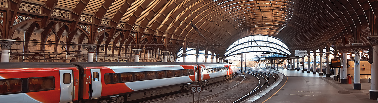 Historische Bahnhofshalle mit gewölbter Dachkonstruktion und weitläufigem Bahnsteigdesign.