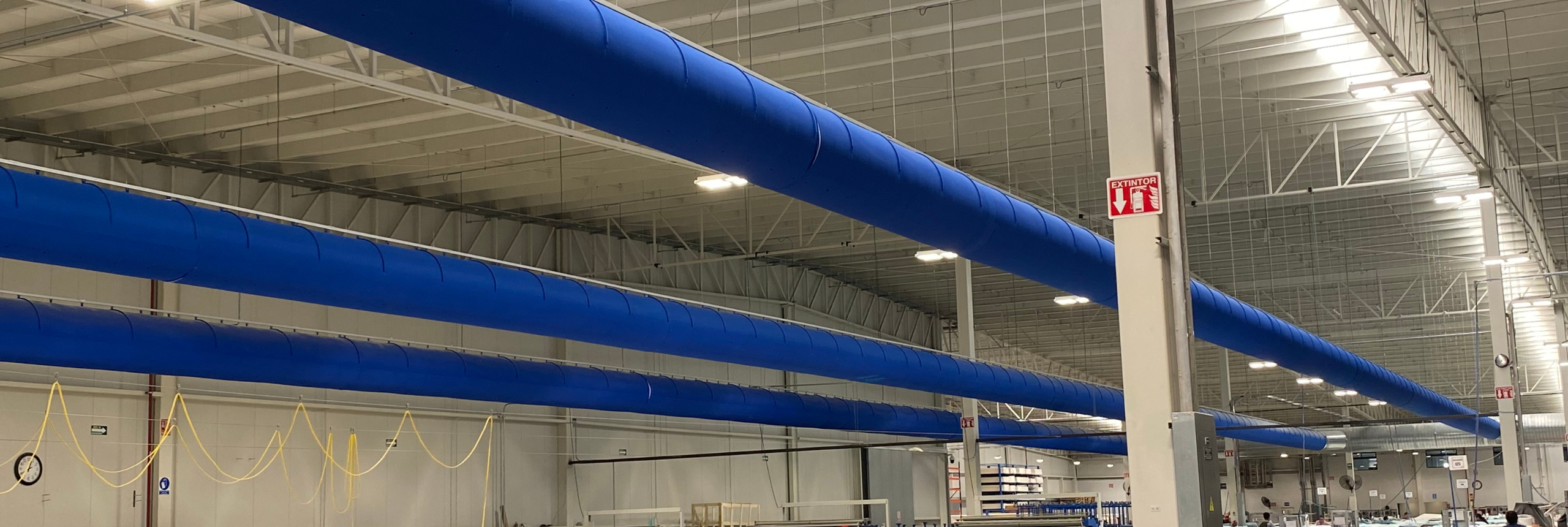 Großflächige Industrieanlage mit parallel verlaufenden blauen Textilluftkanälen zur gleichmäßigen Luftverteilung.