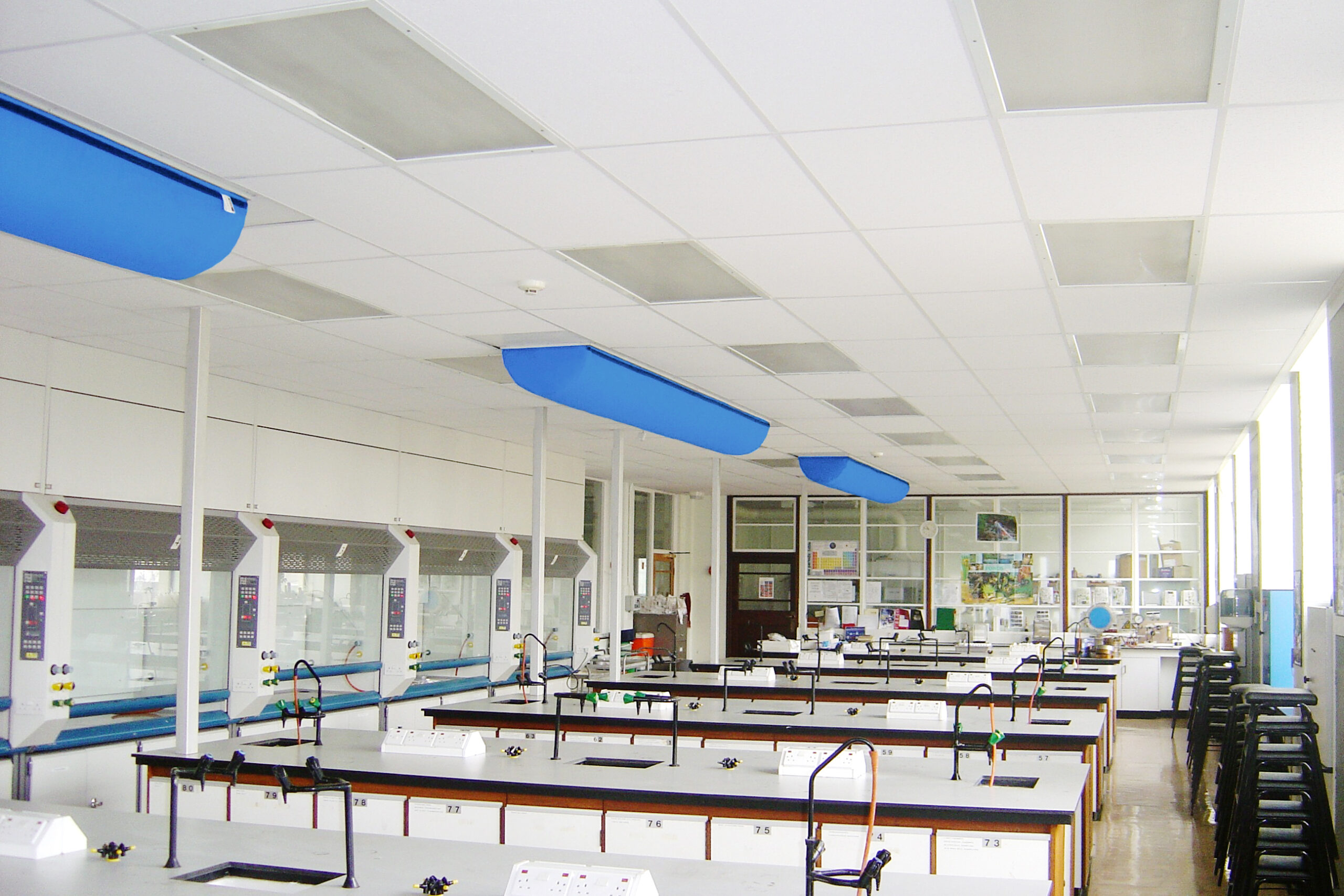Laborraum mit blauen textile luftauslässe über den Arbeitsplätzen und integrierten Abzügen für kontrollierte Luftführung.