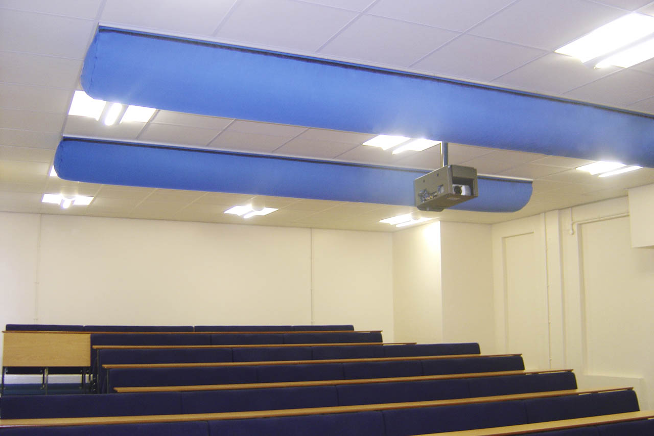 Hörsaal mit blauen Textil-Luftkanälen an der Decke, Reihenbestuhlung und Deckenprojektor in einem modernen Unterrichtsraum.