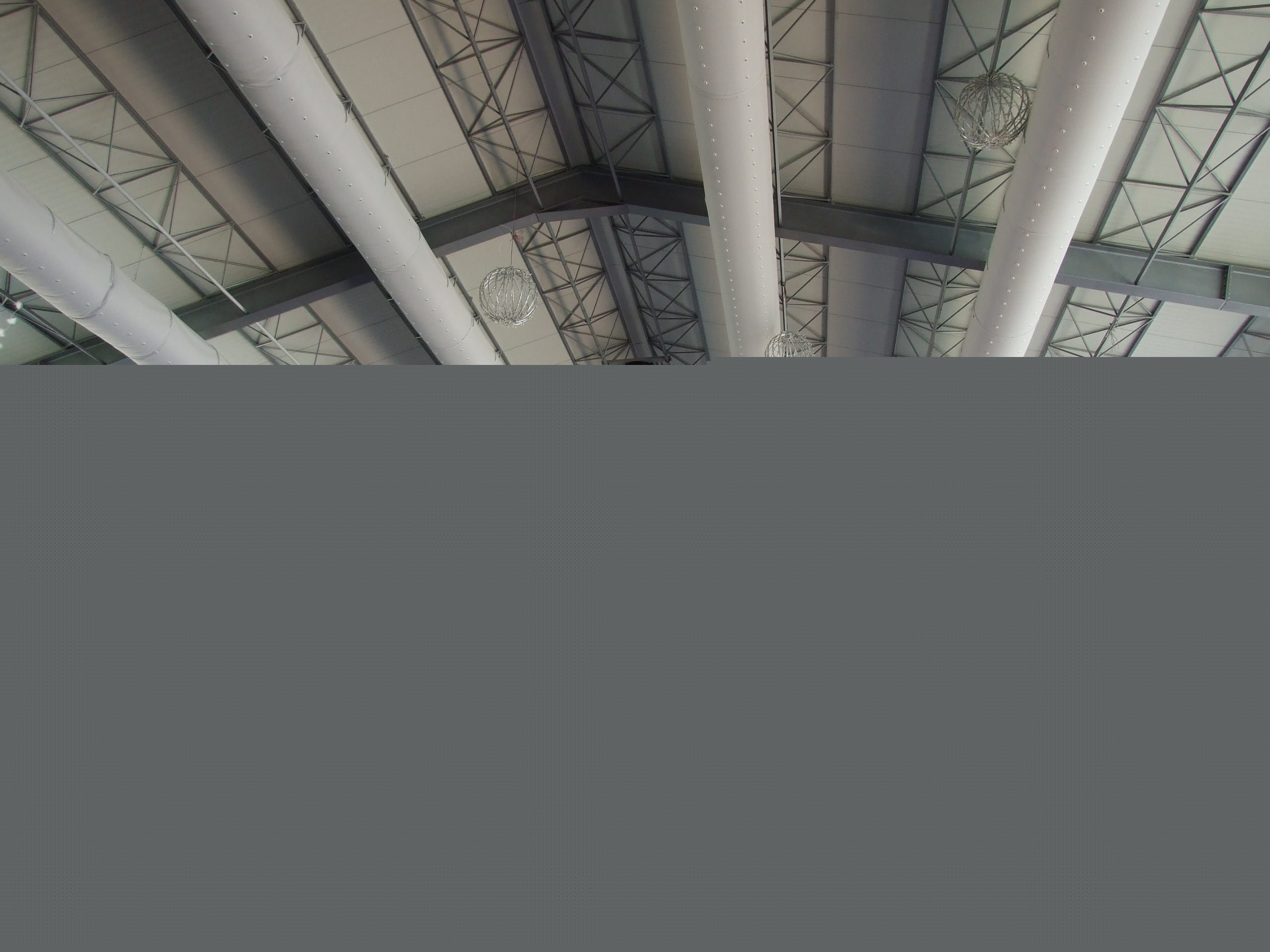 Decke einer großen Industriehalle mit parallel geführten Textilluftkanälen zwischen Stahltragwerken.