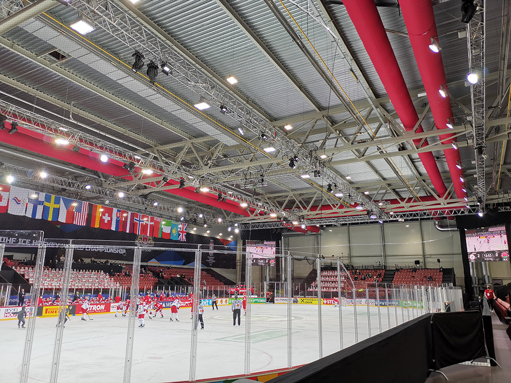 Eishockeyarena mit abgehängten roten Textilluftkanälen innerhalb der Stahl-Dachkonstruktion.