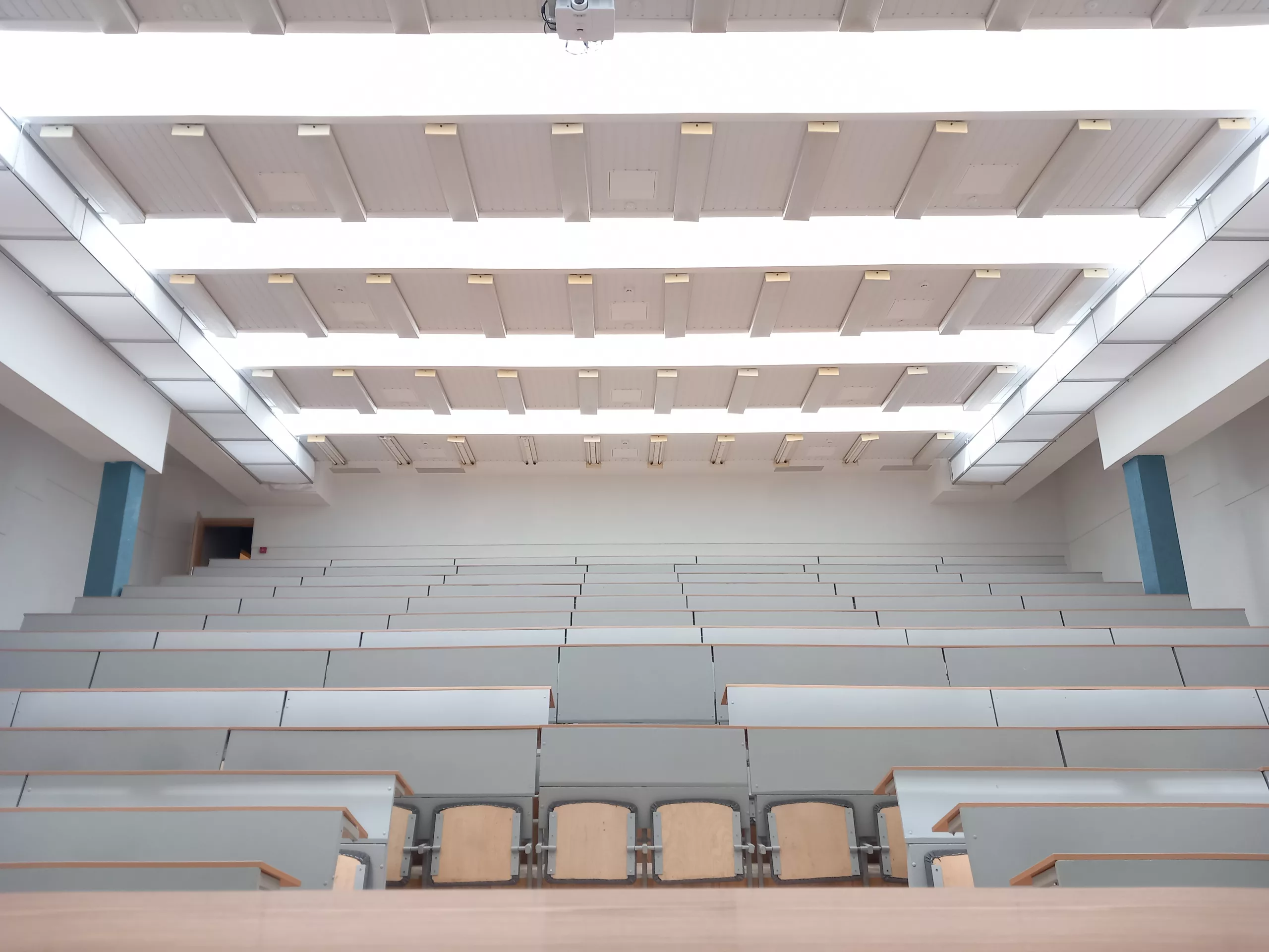 Moderner Hörsaal mit ansteigender Sitzanordnung und integriertem linearem Deckenbeleuchtungssystem.