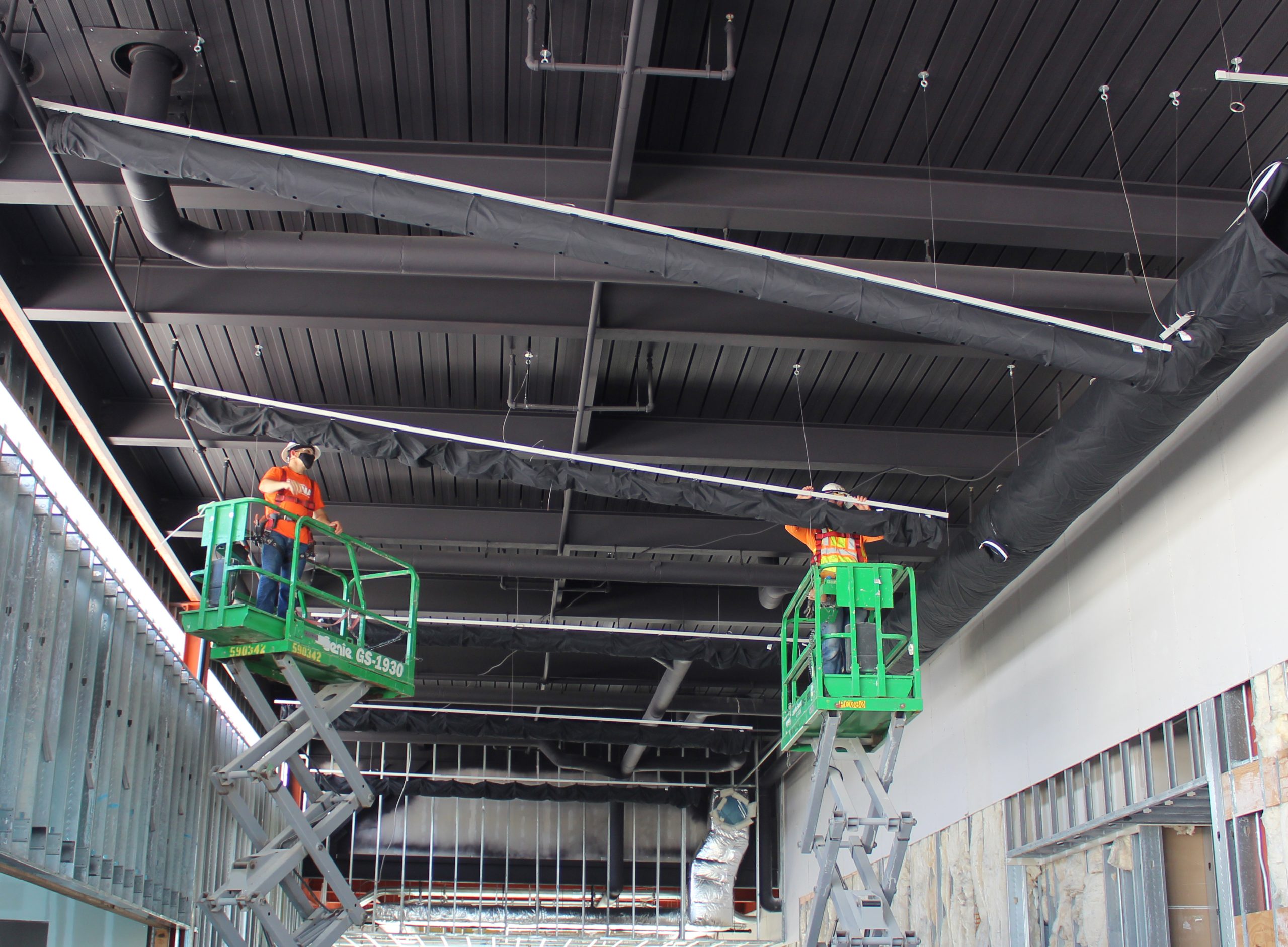 Schwarze Textilkanäle während der Installation an der Decke eines Gebäudes im Rohbau.