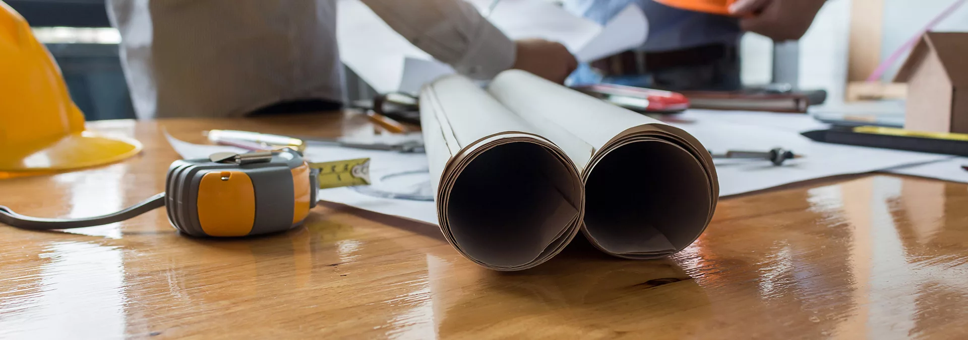 Rouleaux de plans de construction et outils posés sur une table de chantier, FR