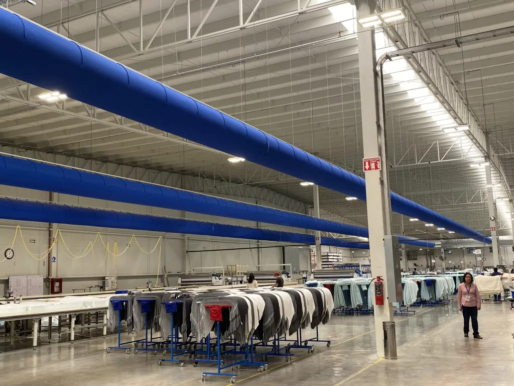 Bright blue FabricAir ducts are installed in the Sunds Textiles manufacturing facility in Mexico to cool the occupied space. The result is an energy efficient, comfortable working environment that also keeps important machinery cool.