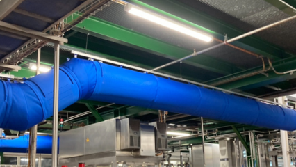 FabricAir ducts in bright blue fabric with laser-cut holes for air delivery are installed in a beverage manufacturing facility in Southern Germany.