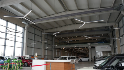 Gray fabric ducts with custom-engineered airflow through laser cut holes provide optimal comfort in an automotive showroom with high ceilings