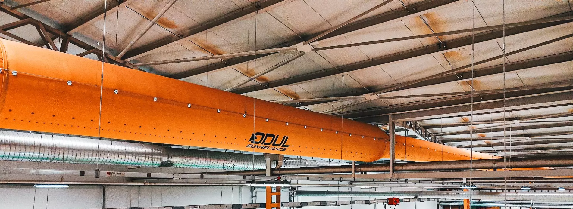 Yellow fabric air ducts with the Odul Solar logo hang in their manufacturing facility