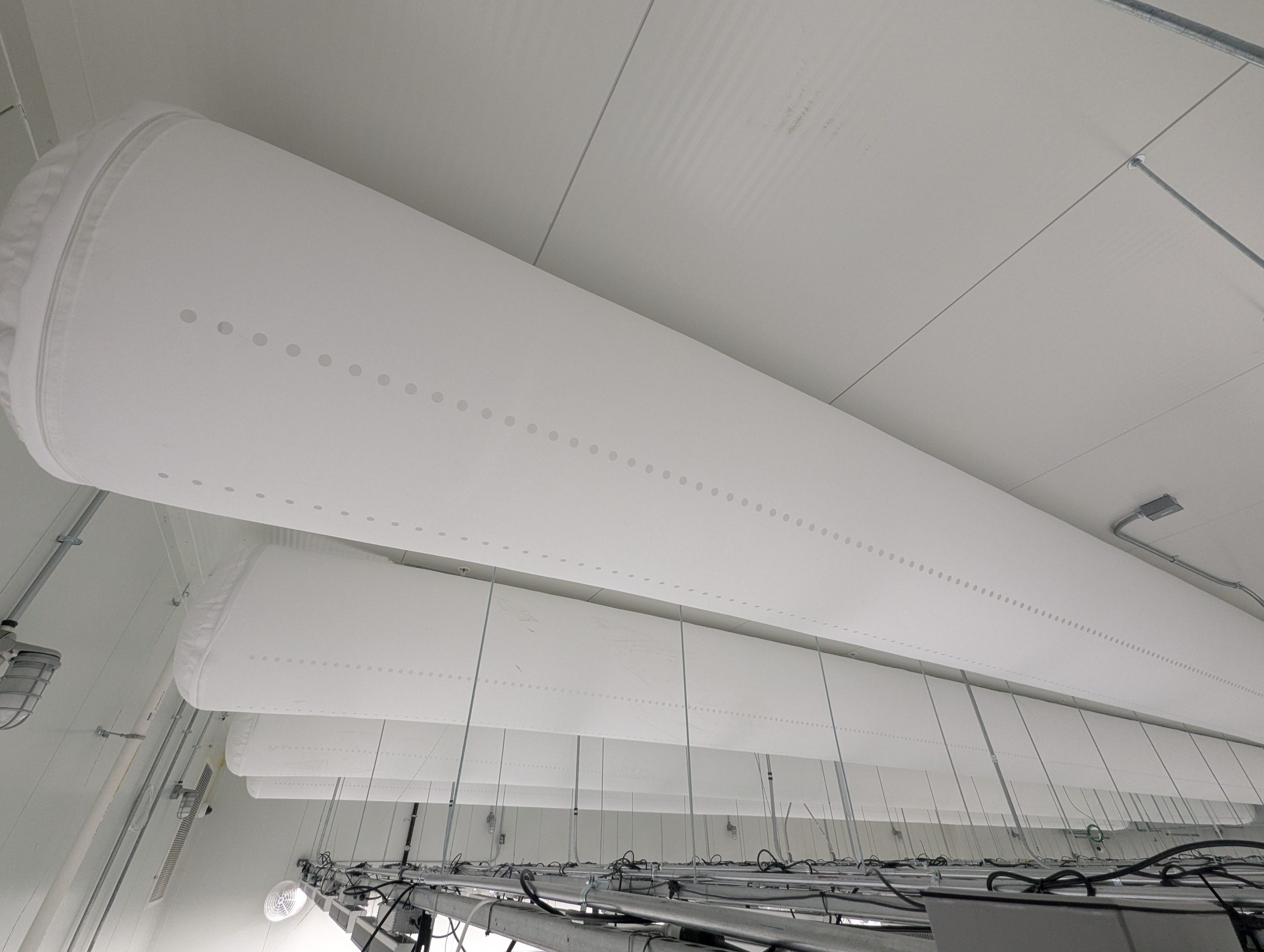 White fabric ducts with rows of air holes along the ceiling of a Native Sun cannabis flower room