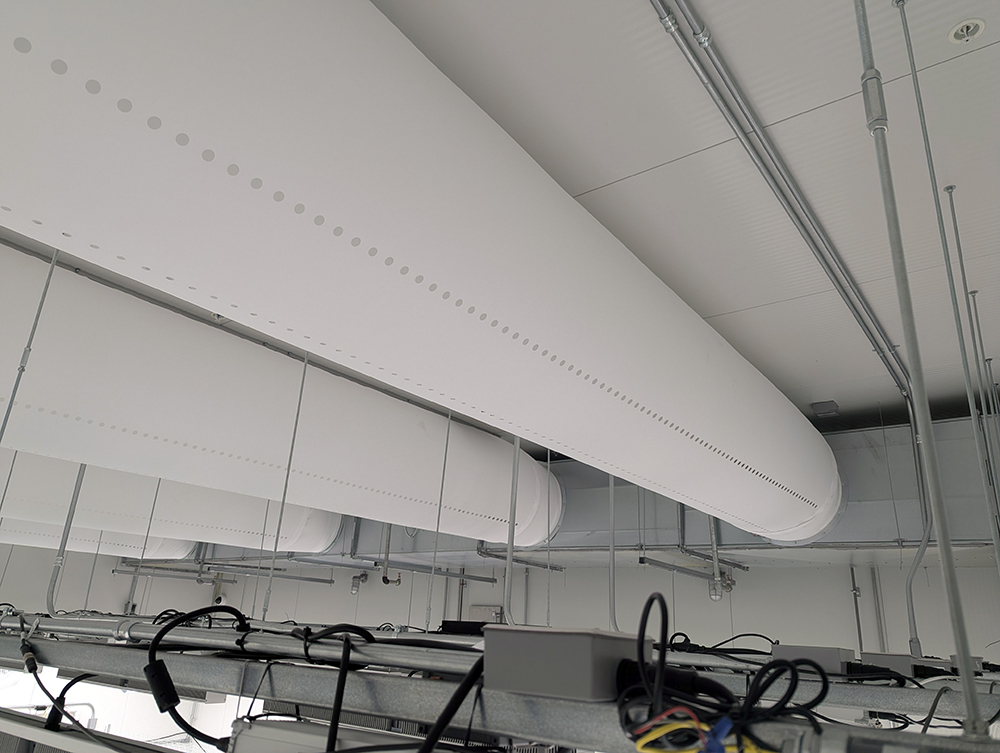 Close-up of white fabric ducts with air holes above the grow light rails in a cannabis flower room