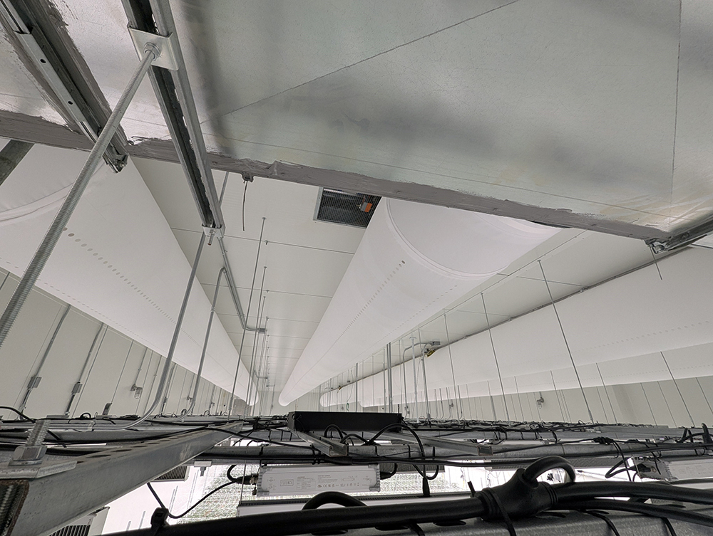 View along a cannabis flower room ceiling with white fabric ducts above the lighting racks