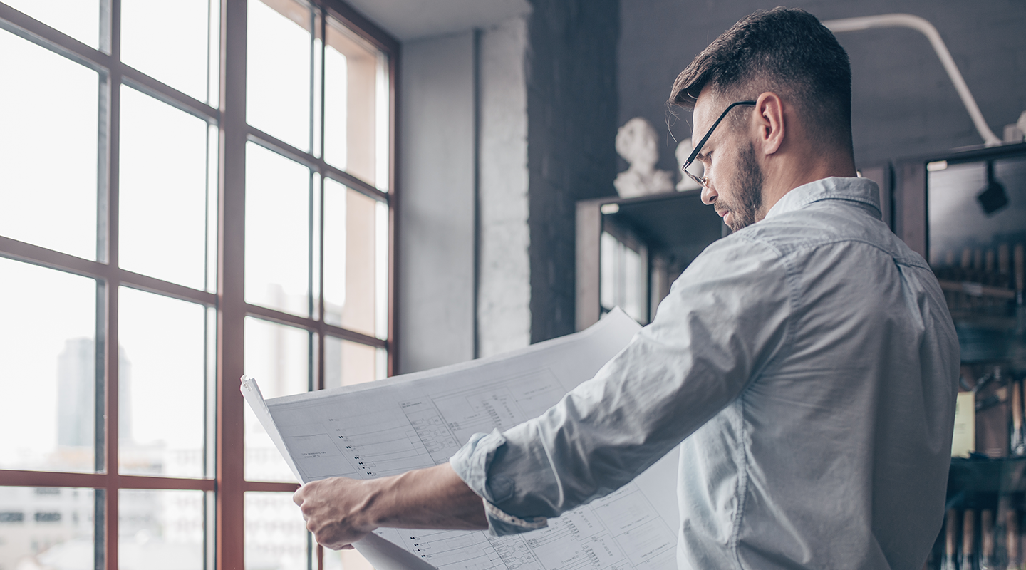 Engineer analyzing a product blueprint inside an office