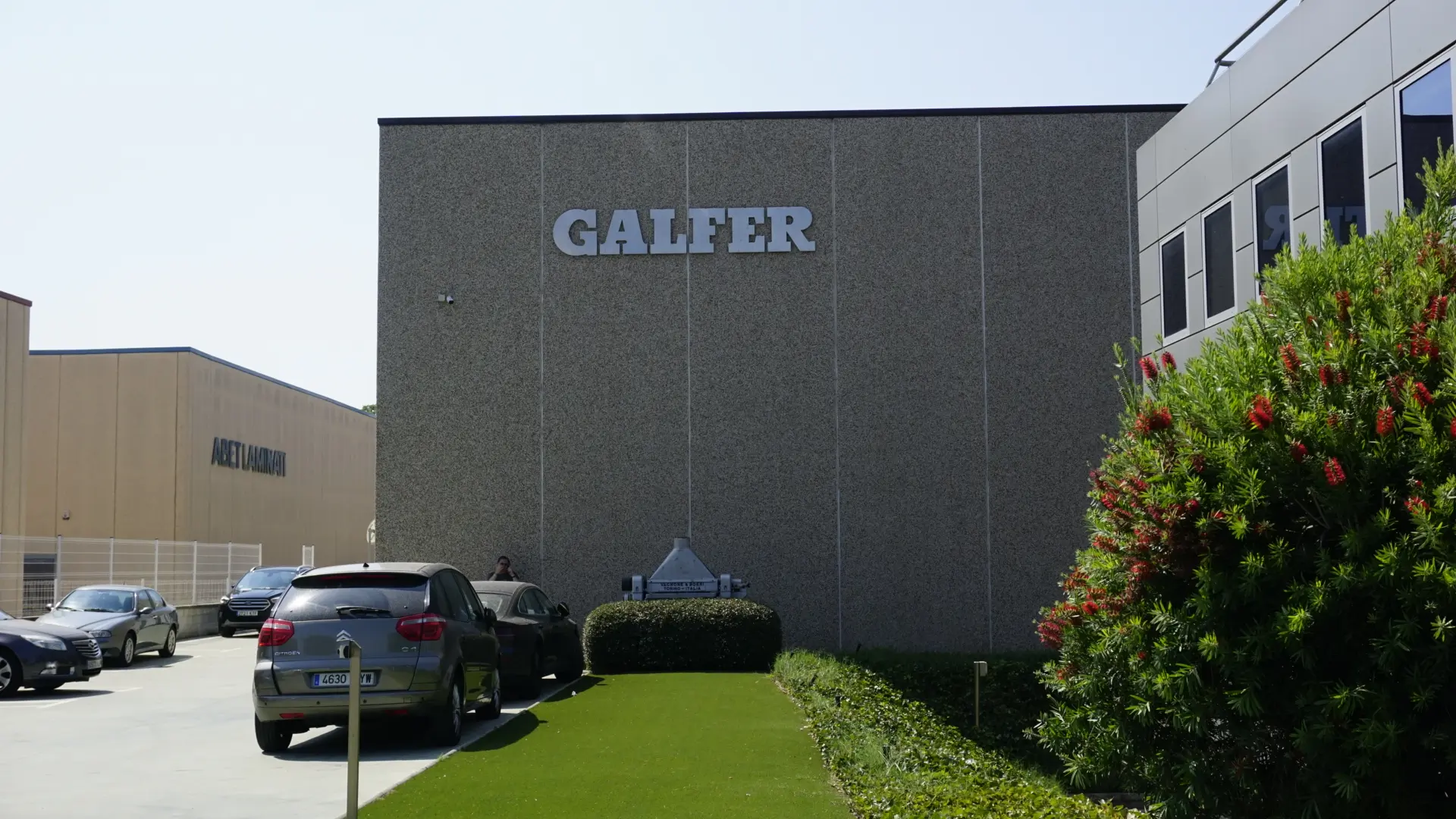 FabricAir fabric ducts in dark gray Combi 20 and Combi 30 fabric with a custom logo installed in the Galfer Production facility in Spain. The duct is suspended from the open ceiling using FabricAir Type 08 suspension with All-in-One for shape retention even when the duct is turned off.