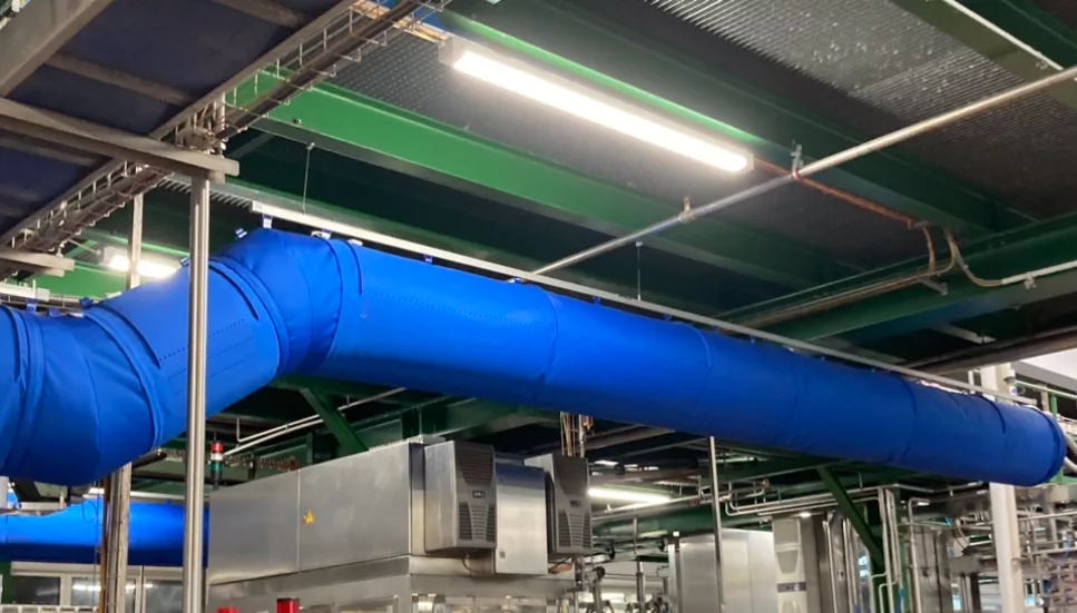 FabricAir ducts in bright blue fabric with laser-cut holes for air delivery are installed in a beverage manufacturing facility in Southern Germany.