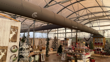 FabricAir ducts in gray fabric featuring custom logos and All-In-One duct shape retention are installed in the Flores Castillon greenhouse and nursery in Barbastro, Spain.