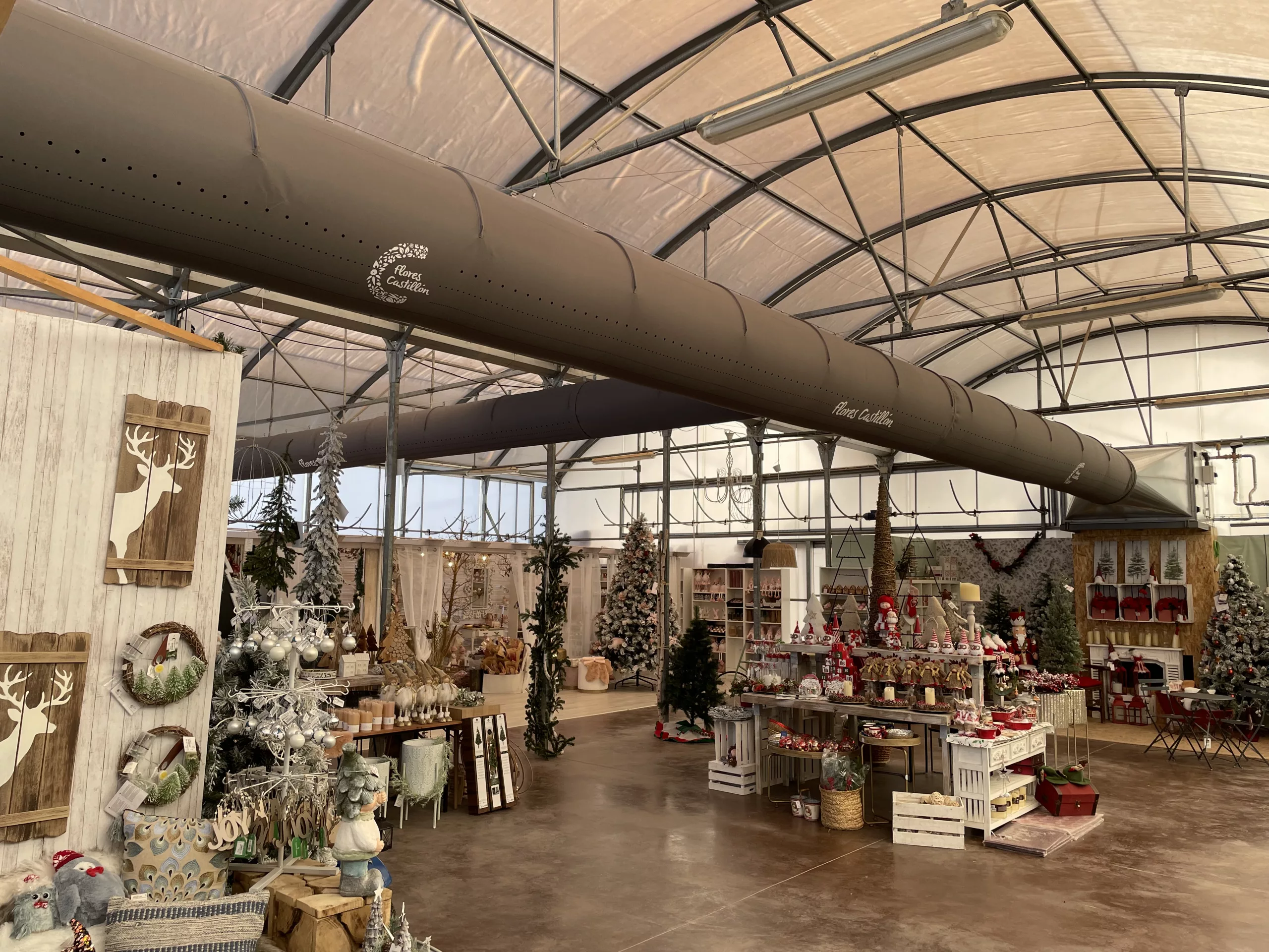 FabricAir ducts in gray fabric featuring custom logos and All-In-One duct shape retention are installed in the Flores Castillon greenhouse and nursery in Barbastro, Spain.
