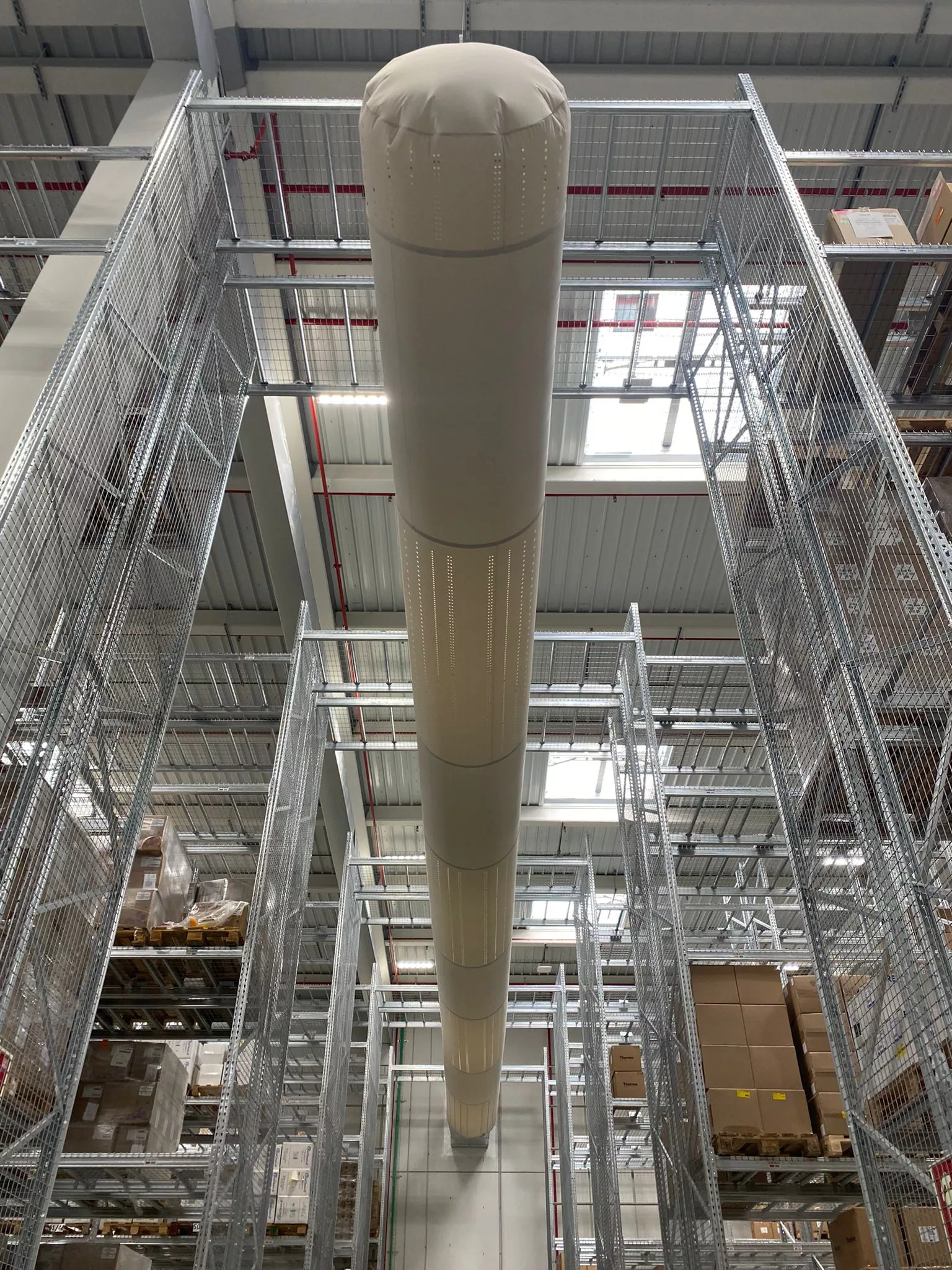 White FabricAir ducts featuring the Thermo Fisher logo are installed in a warehouse in Barcelona Spain to provide precise, uniform airflow without the risk of condensation.