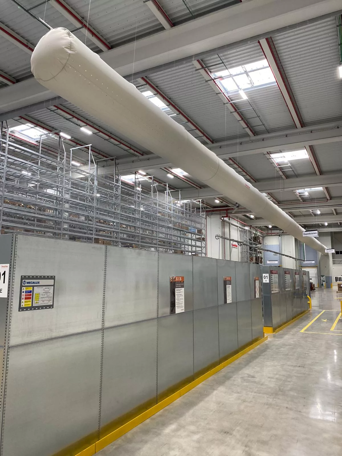 White FabricAir ducts featuring the Thermo Fisher logo are installed in a warehouse in Barcelona Spain to provide precise, uniform airflow without the risk of condensation.