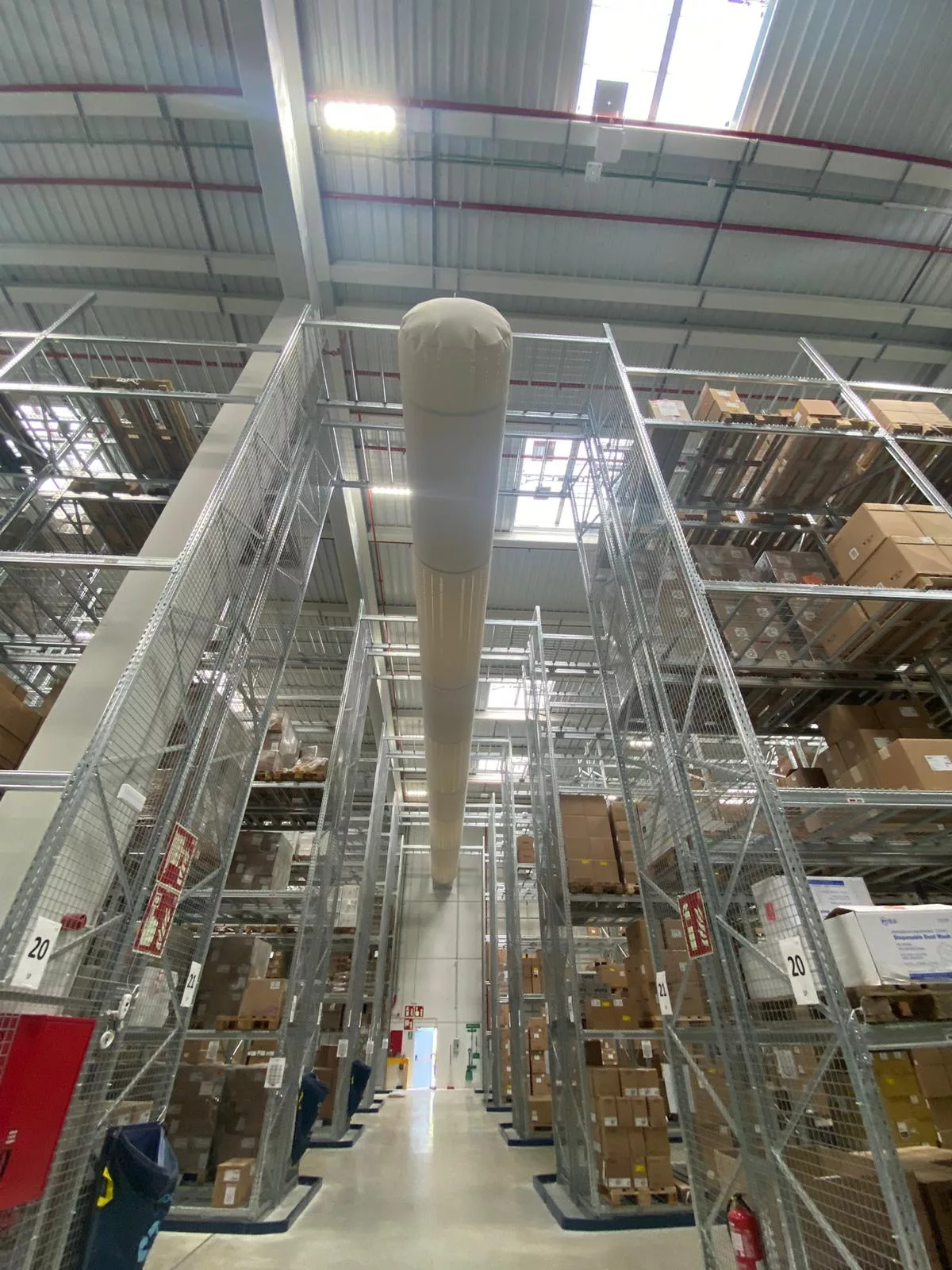 White FabricAir ducts featuring the Thermo Fisher logo are installed in a warehouse in Barcelona Spain to provide precise, uniform airflow without the risk of condensation.