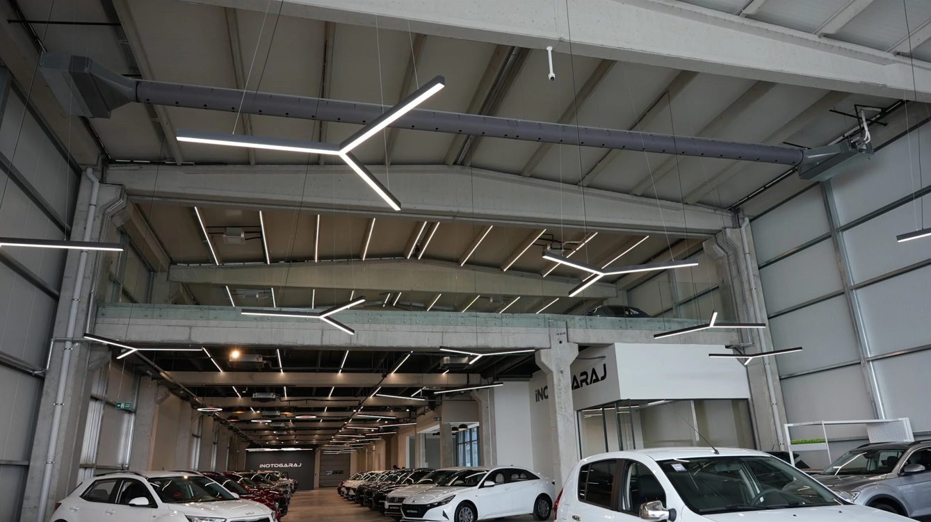 Gray fabric ducts with custom-engineered airflow through laser cut holes provide optimal comfort in an automotive showroom with high ceilings