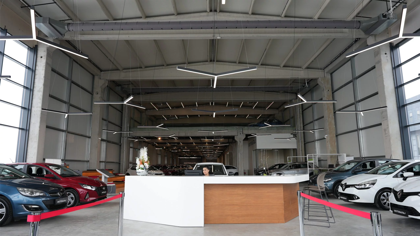Gray fabric ducts with custom-engineered airflow through laser cut holes provide optimal comfort in an automotive showroom with high ceilings