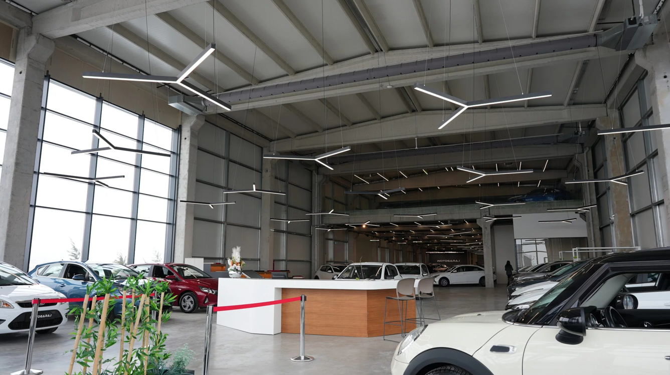 Gray fabric ducts with custom-engineered airflow through laser cut holes provide optimal comfort in an automotive showroom with high ceilings