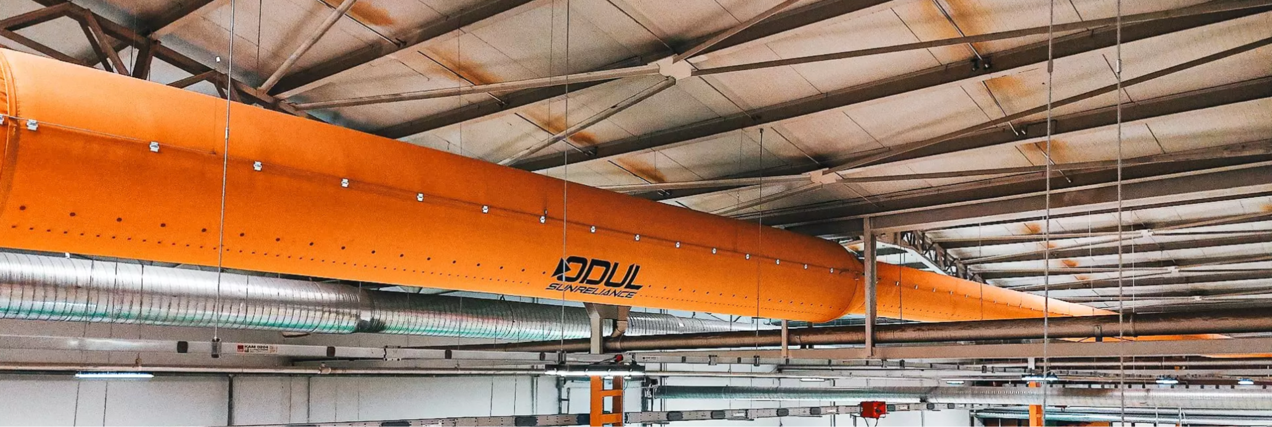Yellow fabric air ducts with the Odul Solar logo hang in their manufacturing facility