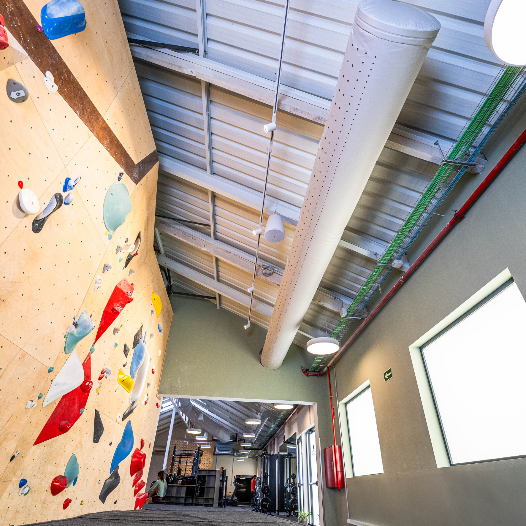 Gray fabric ducting provides draft-free ventilation to enhance comfort and safety at the Sputnik Climbing Gym in Madrid