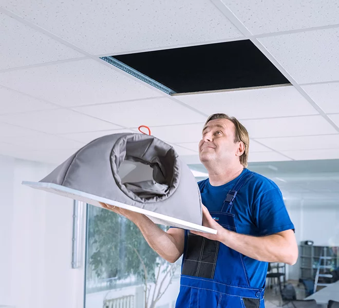 Man installing ceiling diffusers in an office