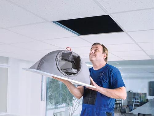 Man installing a ceiling diffuser inside an office